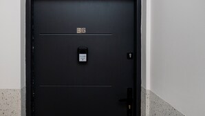 A black door with a digital lock and a label reading 'BookingHost 22 113 14 14'. - Kościuszki Prime Studio (Łódź)