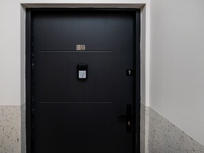 Eine schwarze Tür mit einem digitalen Schloss und einem Schild mit der Aufschrift 'BookingHost 22 113 14 14'.