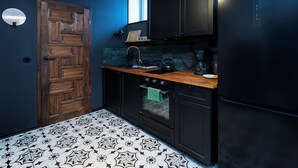 A kitchen with dark cabinetry, a wooden countertop, a black refrigerator, and a patterned floor. - Kościuszki Prime Studio (Łódź)