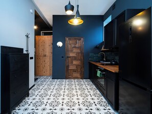 A modern kitchen with a black refrigerator, wooden cabinets, and a patterned floor. - Kościuszki Prime Studio (Łódź)