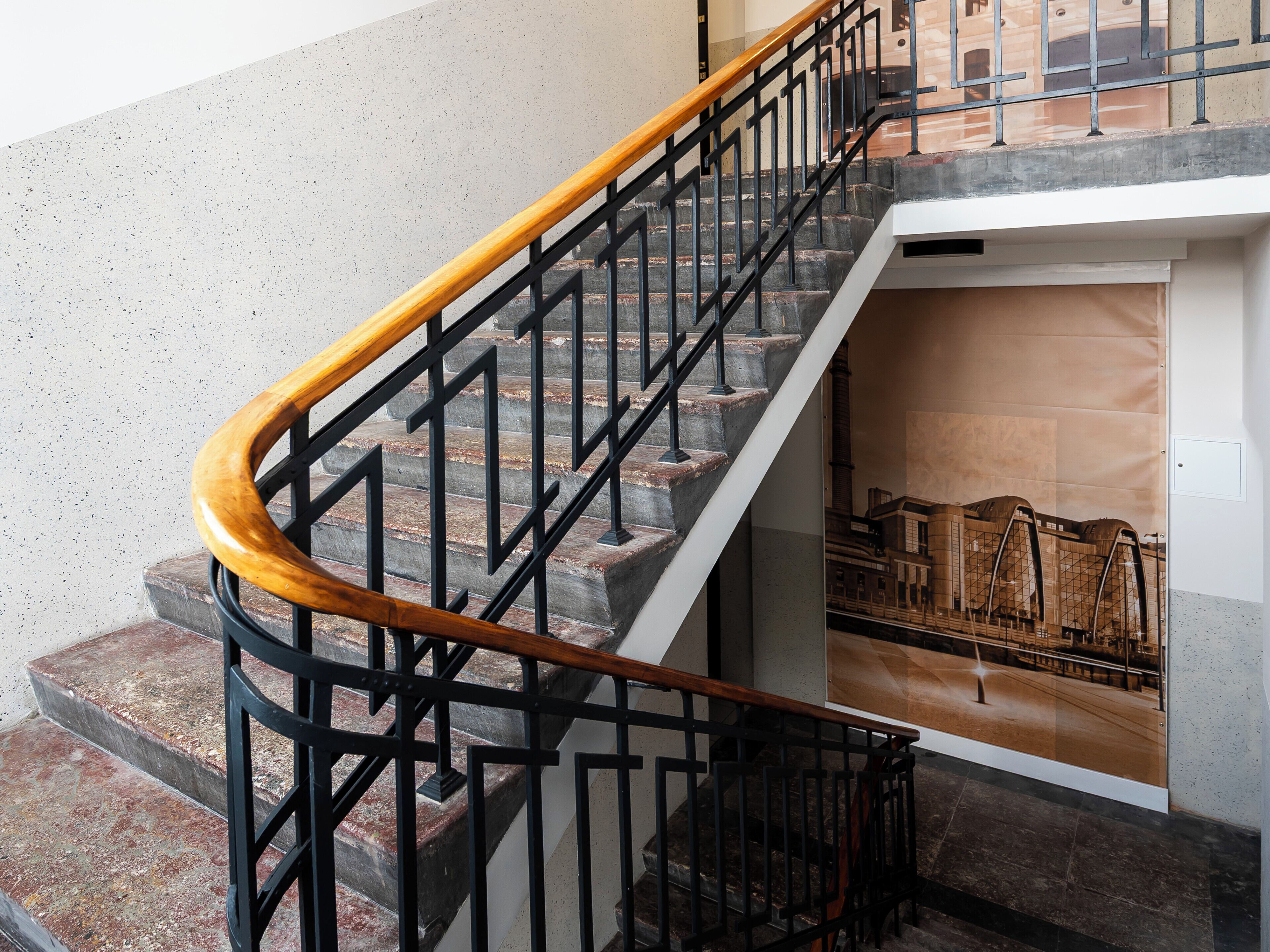 A staircase with a wooden handrail and black metal balusters.