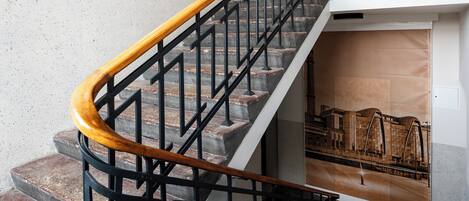 Una escalera con barandilla de madera y balaustradas de metal negro.