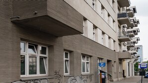 A building with multiple windows and balconies, a parking sign, and a bicycle rack. - Kościuszki Prime Studio (Łódź)