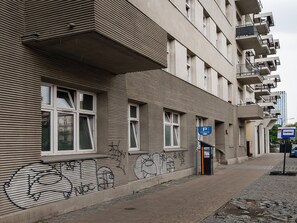 Ein Gebäude mit zahlreichen Fenstern und Balkonen, einem Parkschild und einem Fahrradständer.