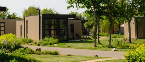A modern building with a glass facade, surrounded by a well-maintained garden with a pathway leading to the entrance.