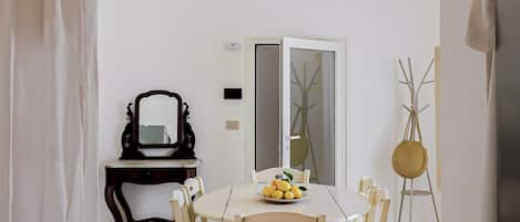 A dining area with a table, chairs, a mirror, and a vase with branches.