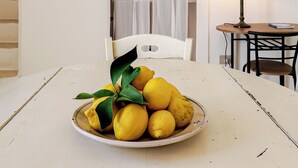 Un comedor con una mesa preparada para dos, un plato de limones, una lámpara y un plato decorativo en la pared.