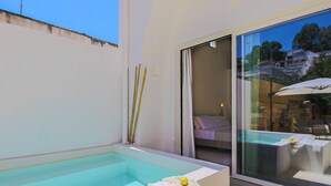 Habitación de hotel moderna con piscina privada, puerta de vidrio que da a un balcón y cama con vistas.