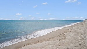 Uma praia com céu limpo e águas calmas.