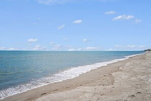 Ein Strand mit blauem Himmel und ruhigem Wasser.
