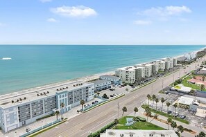 Un hôtel situé sur la côte, avec un parking, une route et une plage en arrière-plan.