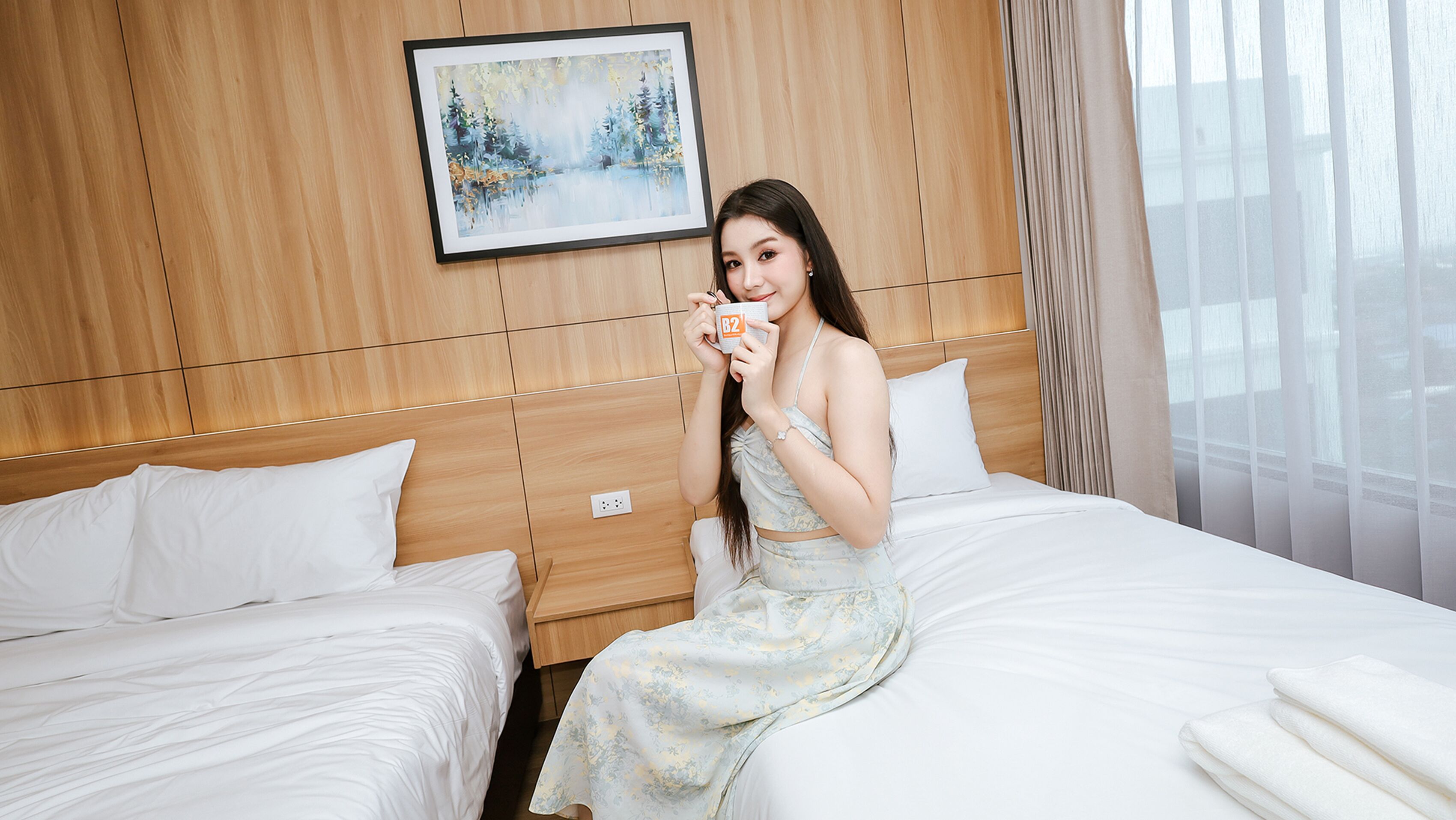 A hotel room with a wooden headboard, a painting of a winter scene, and a bed with white bedding.