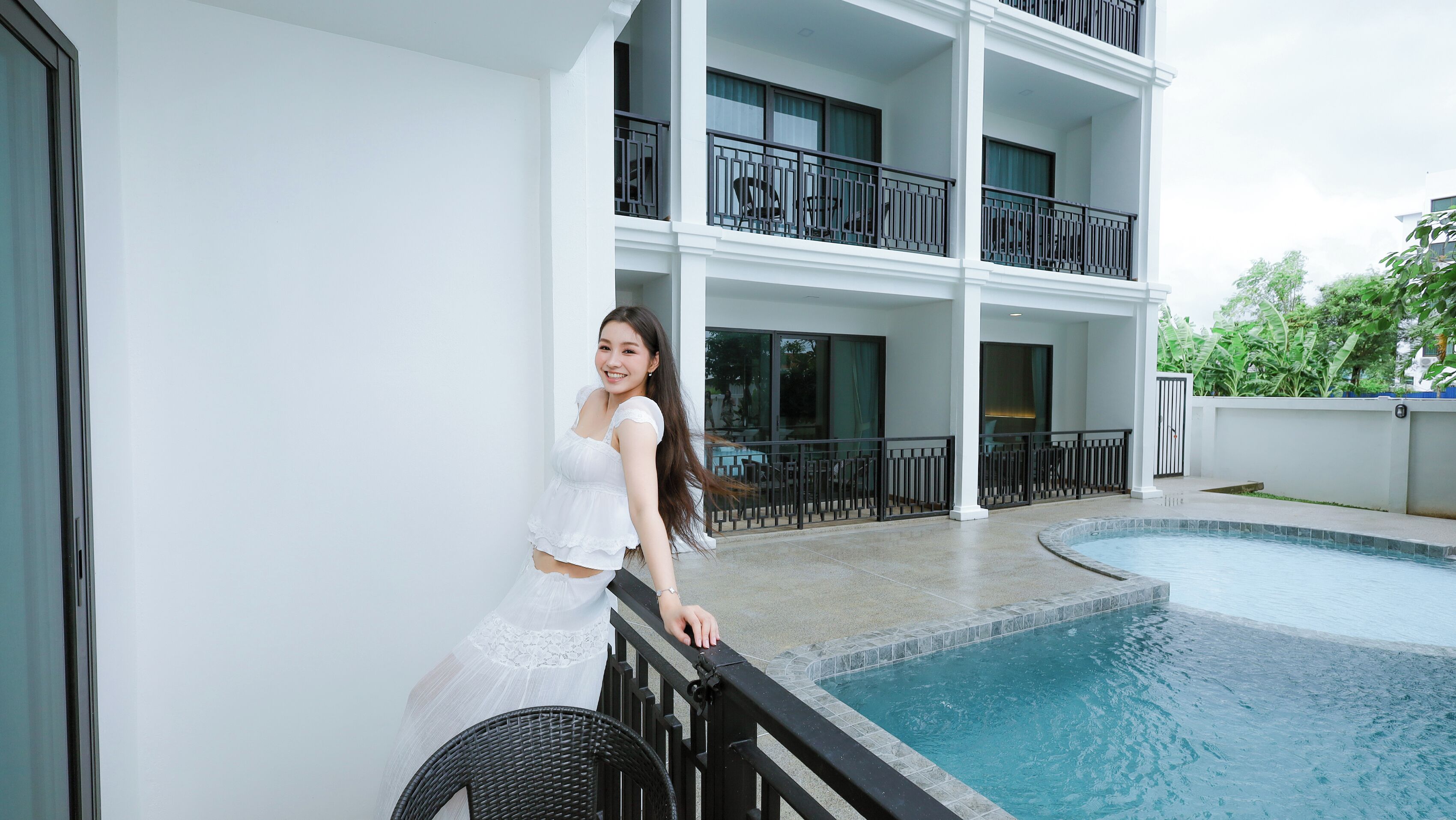 A person standing by a pool with a multi-story building in the background.