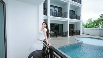 A person standing by a pool with a multi-story building in the background.