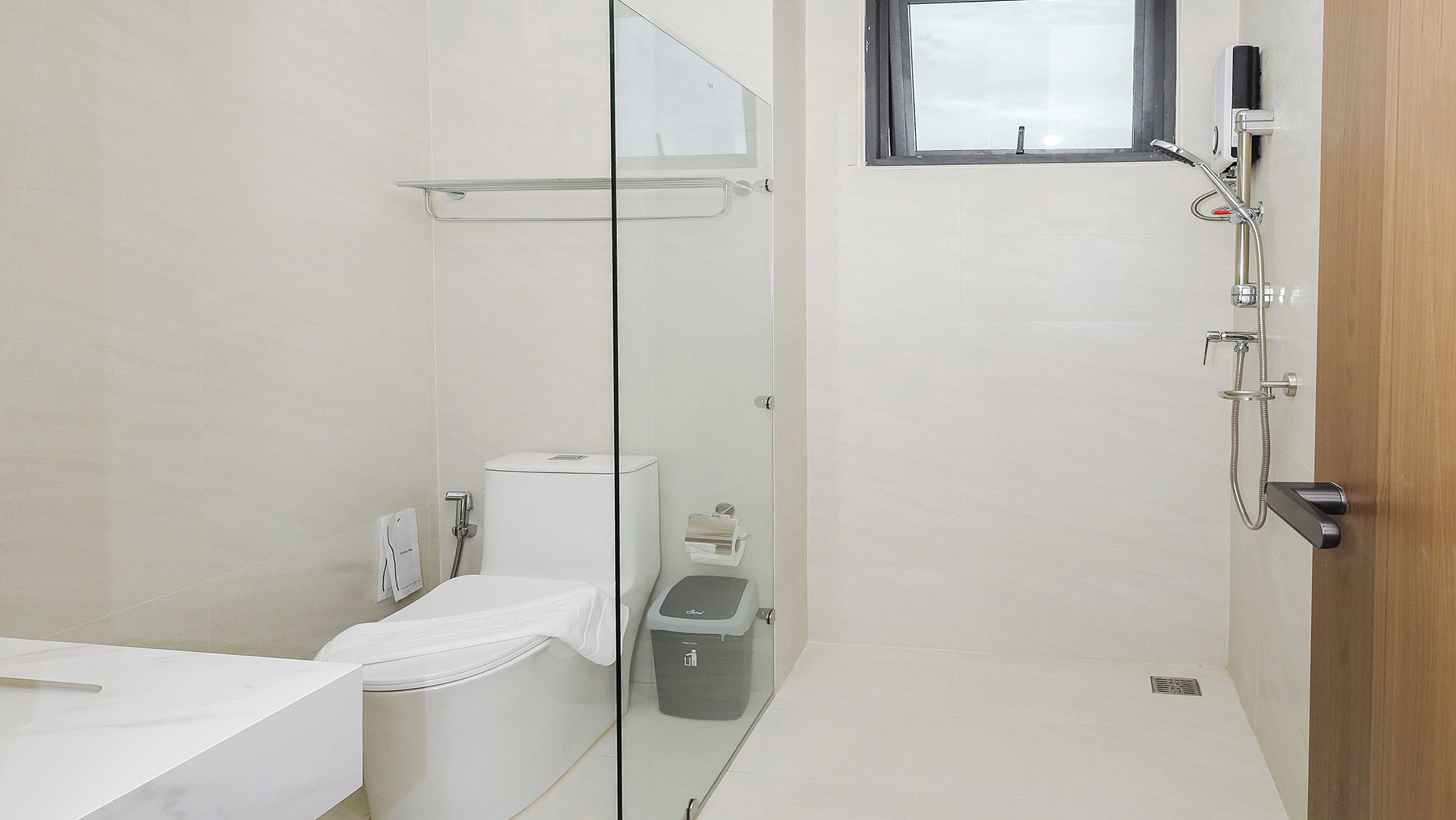 Une salle de bain moderne avec une douche à parois de verre, des toilettes, une poubelle et un lavabo.