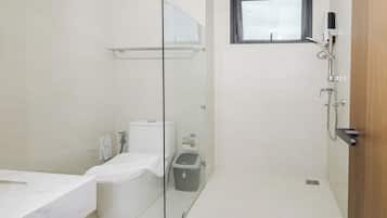 Une salle de bain moderne avec une douche à parois de verre, des toilettes, une poubelle et un lavabo.