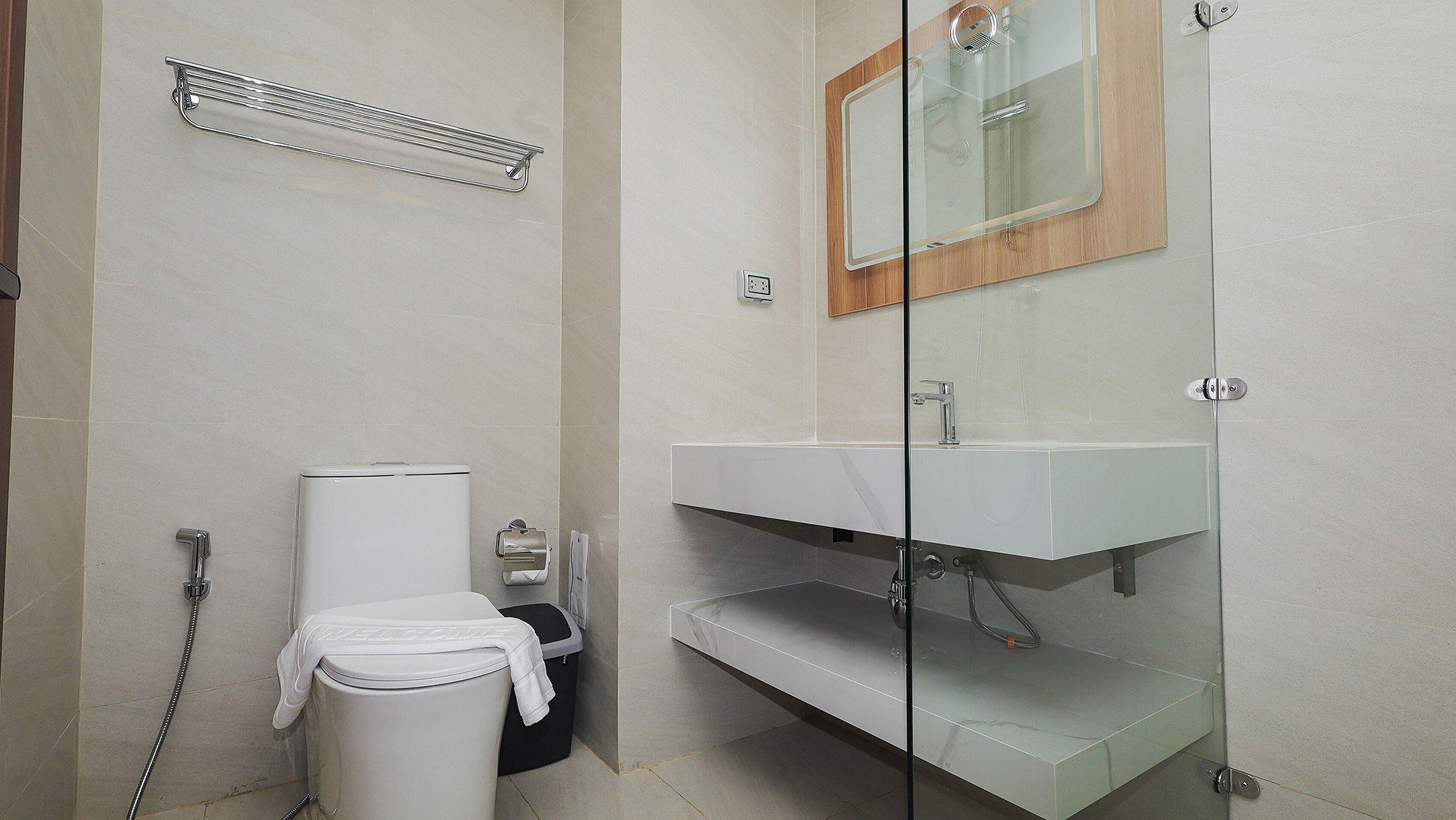 A modern bathroom with a toilet, a shower, and a glass-enclosed sink area.
