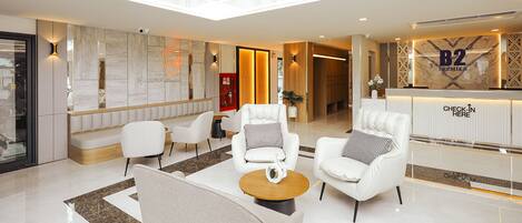 A modern hotel lobby with a reception desk, seating area, and a view of the hallway.