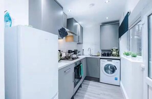 A compact kitchen with a washing machine, a stove, and a sink. - Games Room, Stylish Home, Prime Location, Sleeps (Salford)