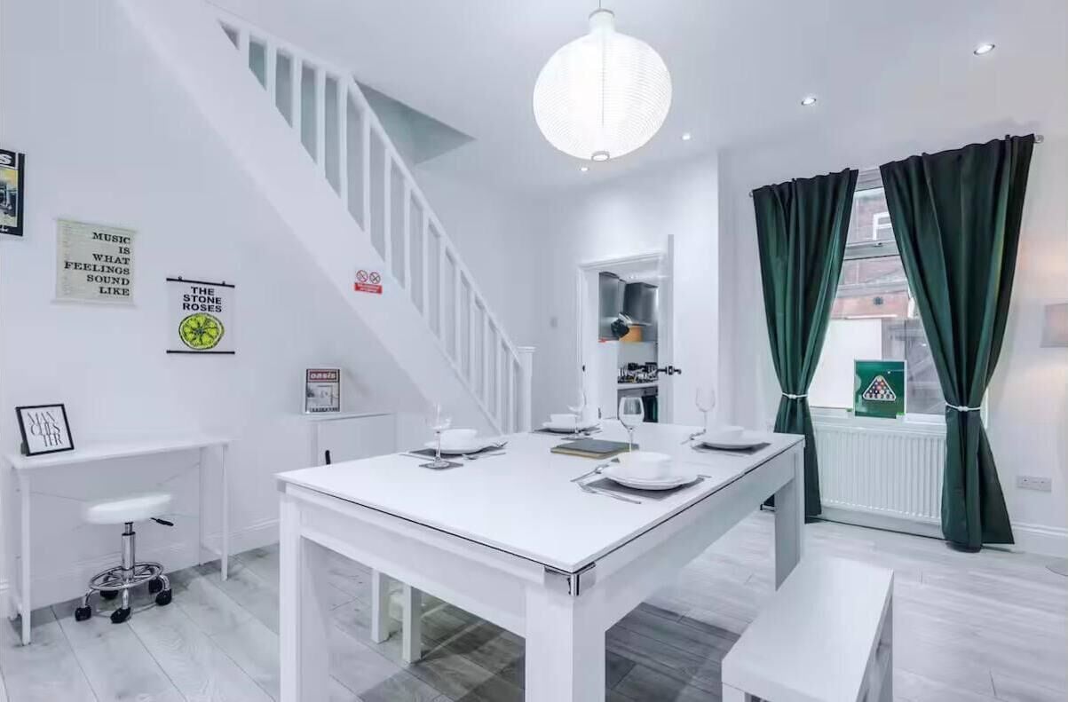 Una cocina moderna con una mesa blanca lista para comer, una escalera y vistas a la calle.