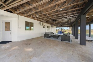 En åben patio med træloft, udendørs møbler og udsigt over landskabet.