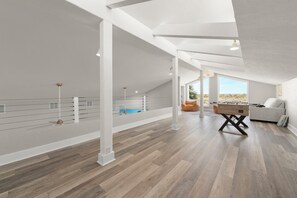 A spacious loft with high ceilings, a wooden floor, a pool, and a cozy seating area. - Sanibel Beach Retreat + Bonus Bungalow! Sleeps 17 • Private Pool (Sanibel)