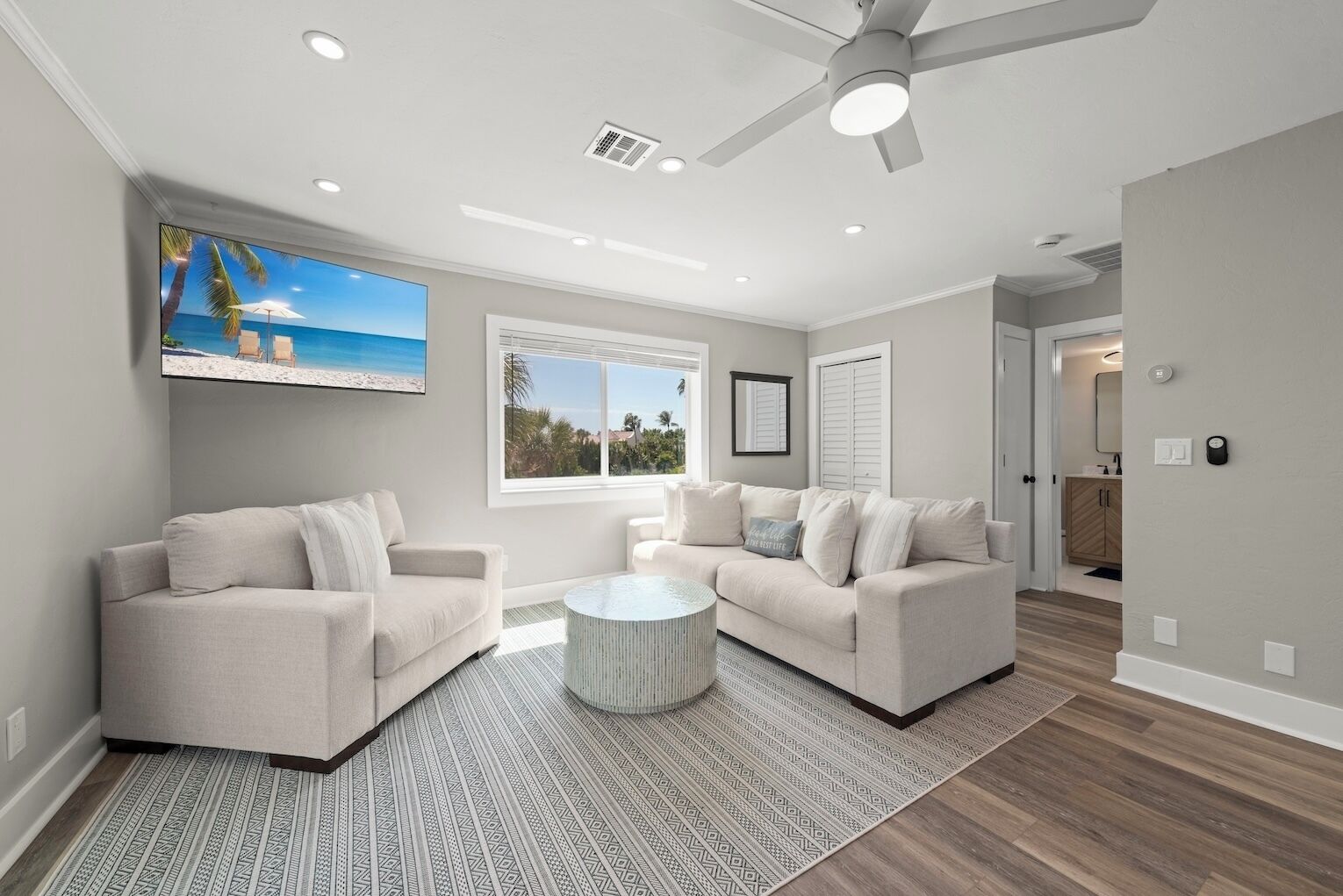A modern living room with two sofas, a coffee table, and a ceiling fan.