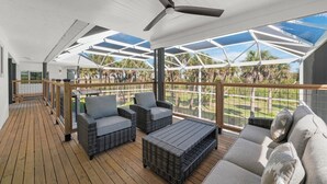 A covered outdoor deck with wicker furniture and a ceiling fan. - Sanibel Beach Retreat + Bonus Bungalow! Sleeps 17 • Private Pool (Sanibel)