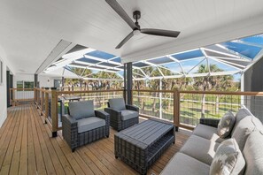 Eine überdachte Terrasse im Freien mit Rattanmöbeln und Deckenventilator.