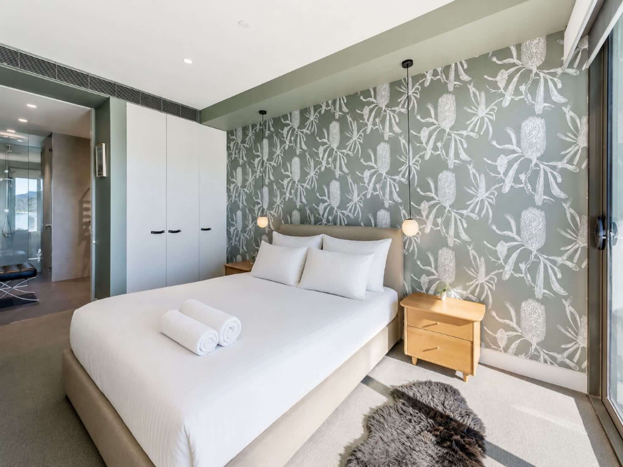 Un dormitorio moderno con una cama grande, una mesita de noche de madera y una alfombra mullida.