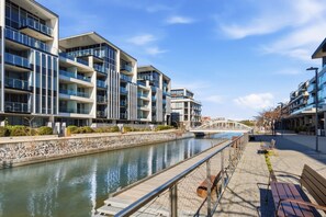 A modern apartment building with balconies, a canal, and a pedestrian bridge. - Waterfront 1-Bed Apartment in Kingston (Kingston)