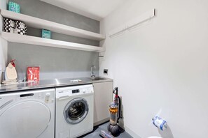 A laundry area with a washing machine, dryer, and a vacuum cleaner. - Waterfront 1-Bed Apartment in Kingston (Kingston)