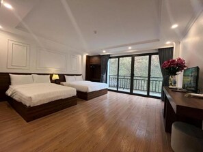A hotel room with a large bed, a desk, and a balcony with a view. - Sapa Warm Hotel (Sa Pa)