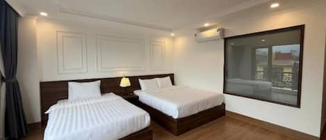 Habitación de hotel con dos camas, un ventanal grande y un equipo de aire acondicionado instalado en el techo.