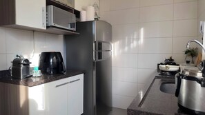 Eine moderne Küche mit einem Edelstahl-Kühlschrank, einer Kaffeemaschine und einem Spülbecken.
