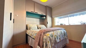 Quarto com cama, janela e armários embutidos.