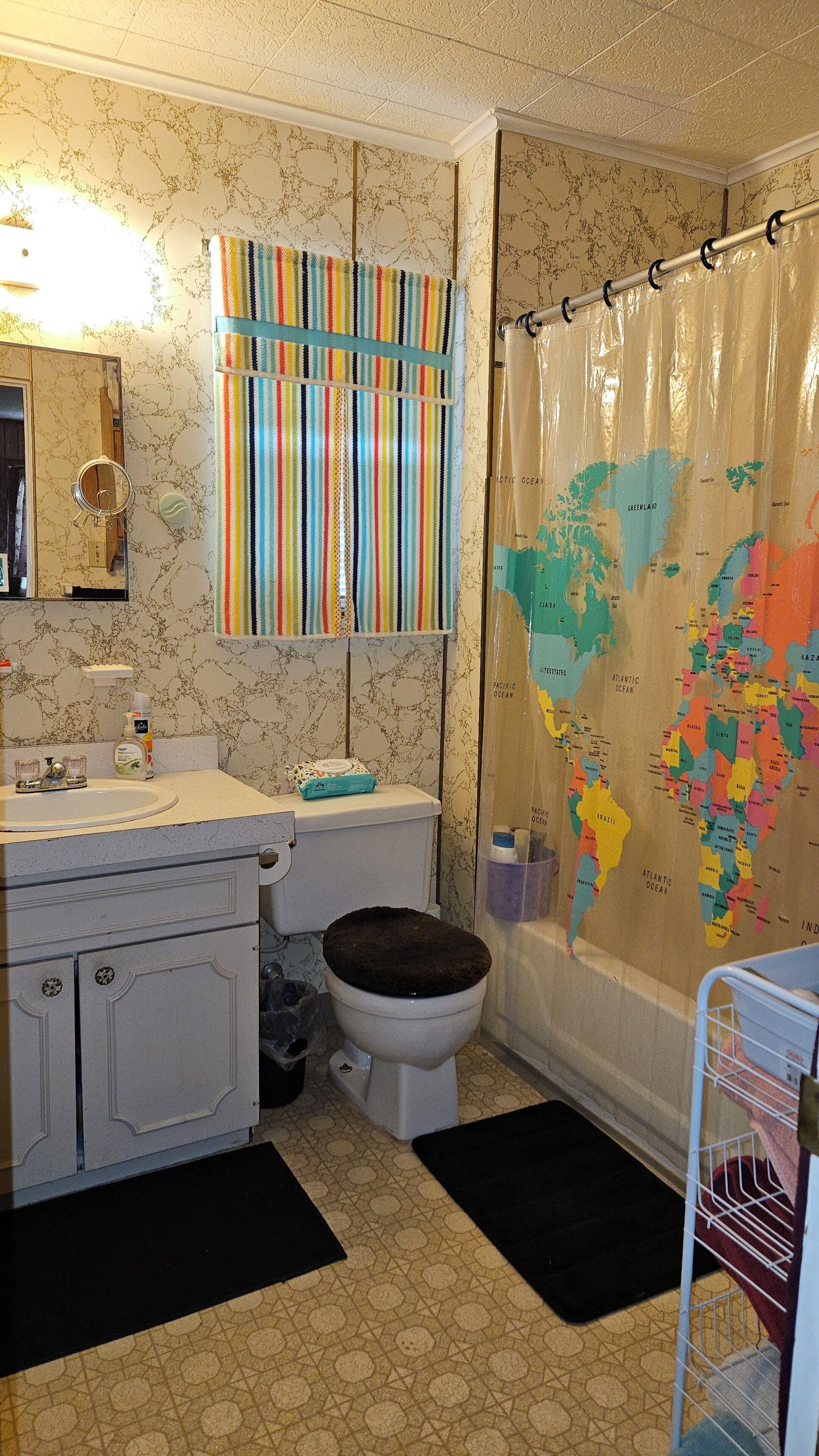 A bathroom with a toilet, sink, and a shower curtain with a world map design.