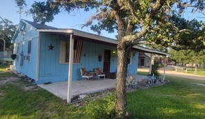 A small house with a porch, a star decoration, and an American flag.