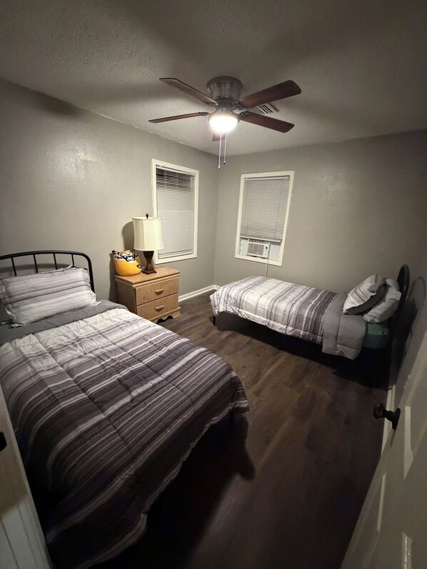 Un dormitorio con dos camas, ventilador de techo y aire acondicionado.