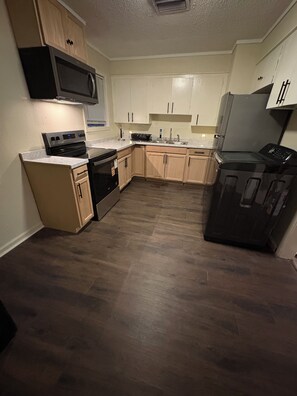 A kitchen with wooden cabinets, a microwave, a stove, and a dishwasher.