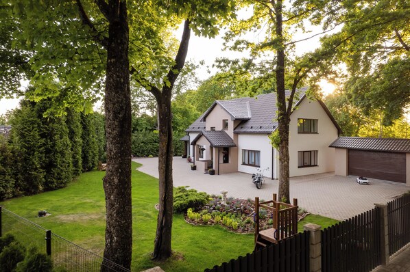 A two-story house with a driveway, a garage, and a fenced garden area.