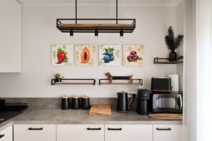 A modern kitchen with a central island, black appliances, and wall-mounted shelves.