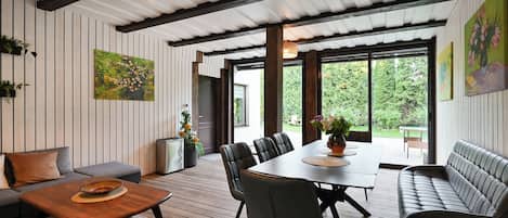 A modern interior with a dining area, sofa, and large windows.