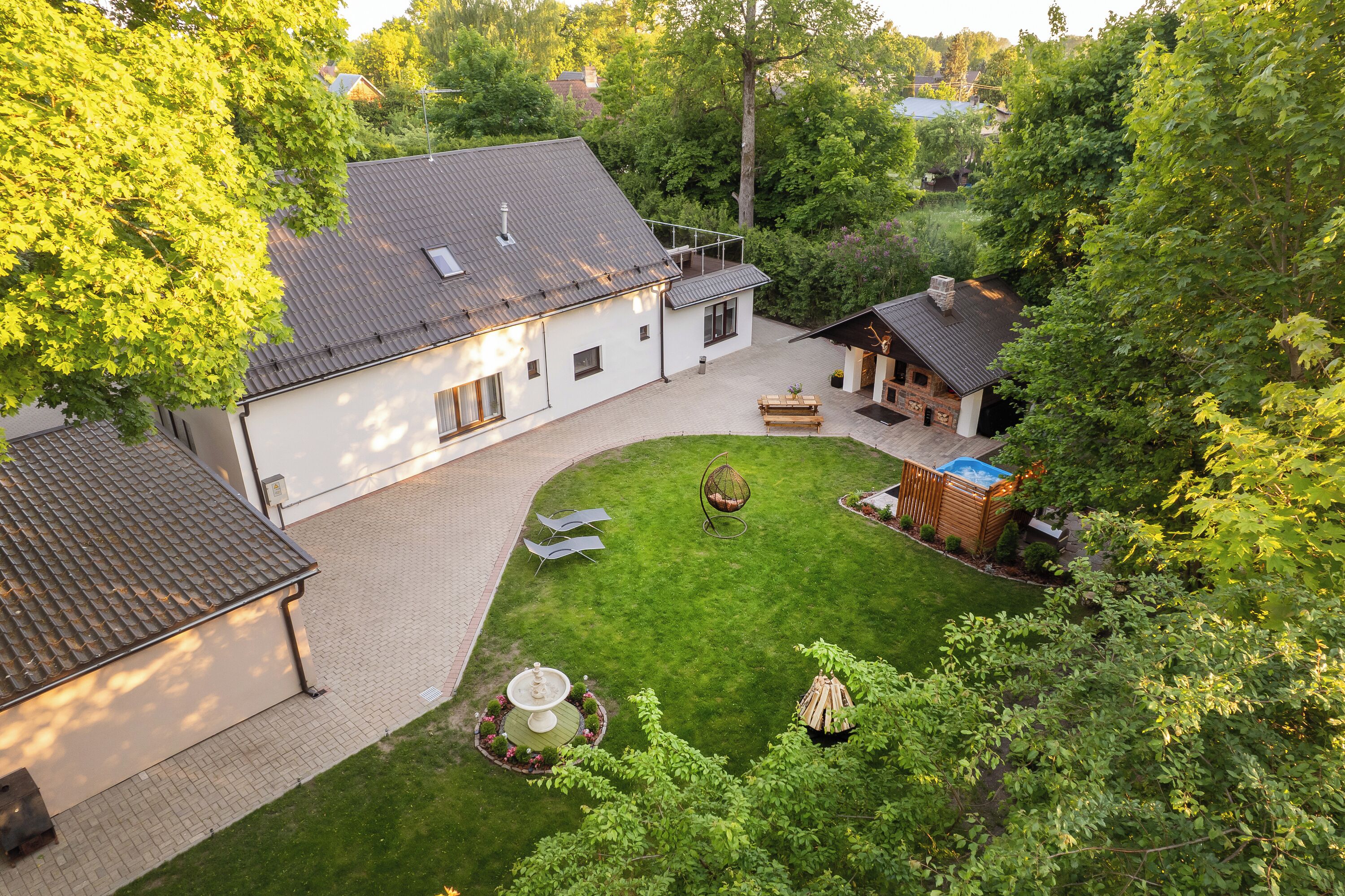 A house with a paved driveway, a lawn, a hanging chair, and a small shed.