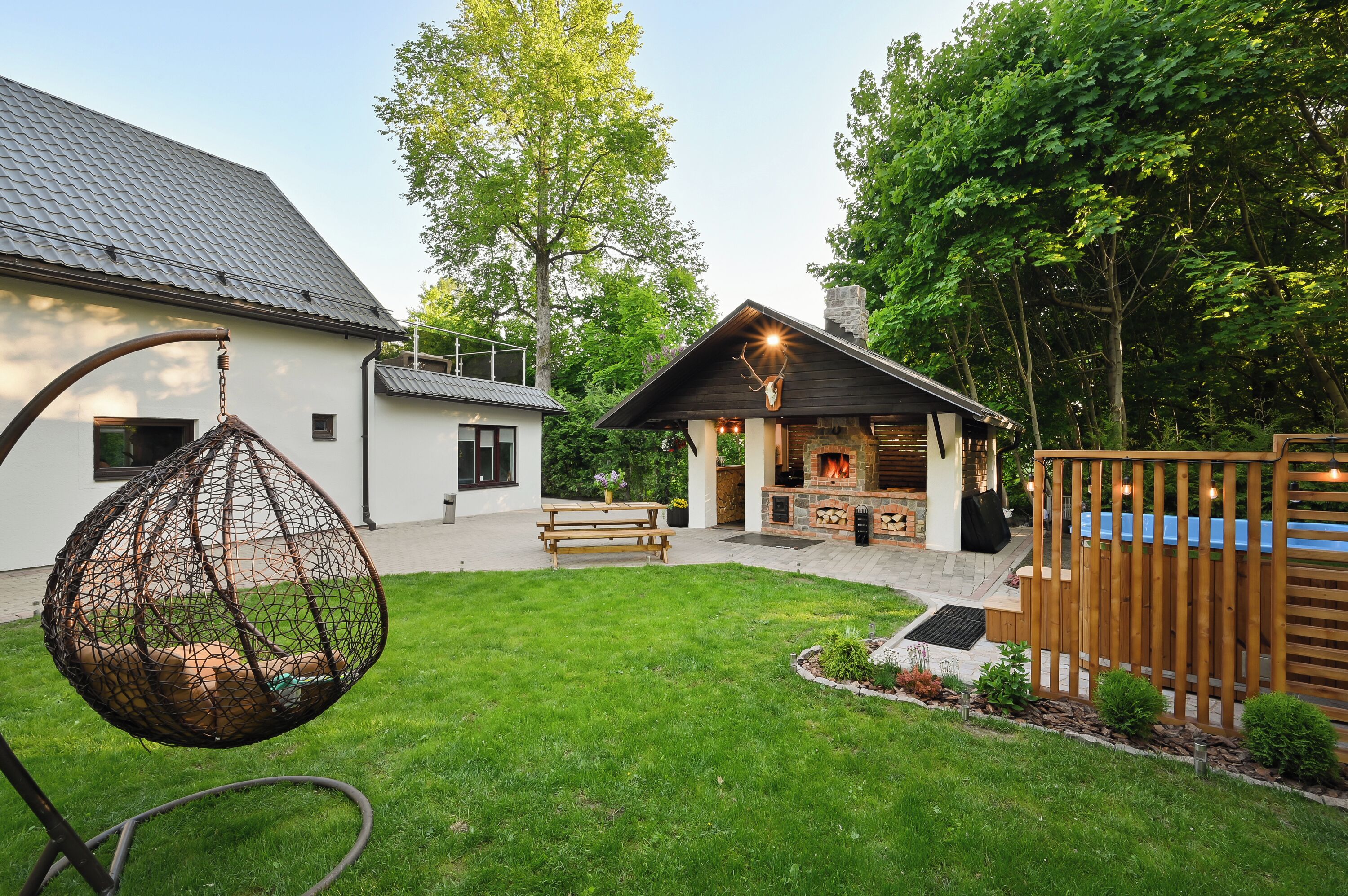 Une maison dotée d’un patio, d’un fauteuil suspendu, d’un espace barbecue et d’une clôture en bois.