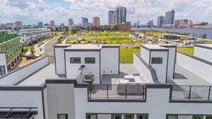 Um edifício moderno com terraço no telhado, vista para o horizonte da cidade e um rio ao fundo.