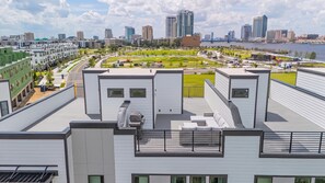 A modern building with a rooftop patio, a view of the city skyline, and a river in the background. - Luxury 3BR Waterfront w/ Private Rooftop Skyline Views (Jacksonville)