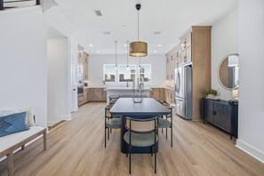 A modern kitchen with a dining table, chairs, and a large window. - Luxury 3BR Waterfront w/ Private Rooftop Skyline Views (Jacksonville)