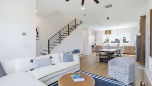 Uma sala de estar moderna com escada, área de jantar e cozinha.