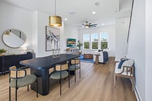 A modern kitchen with a dark wooden table, four chairs, and a ceiling fan. - Luxury 3BR Waterfront w/ Private Rooftop Skyline Views (Jacksonville)
